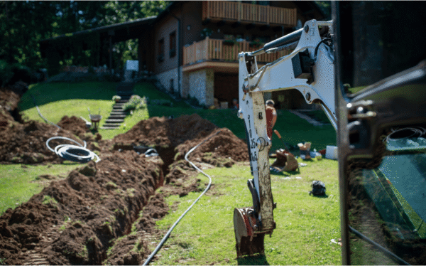 Excavator digging trench for drainage installation on residential property in Ontario